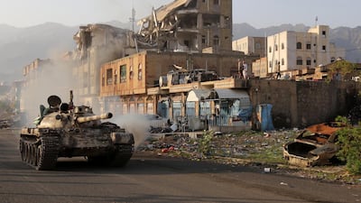 Yemeni fighters loyal to President Abdrabu Mansur Hadi ride a tank past a destroyed building during clashes with Houthi rebels in the country’s third city of Taez on May 30. AFP
