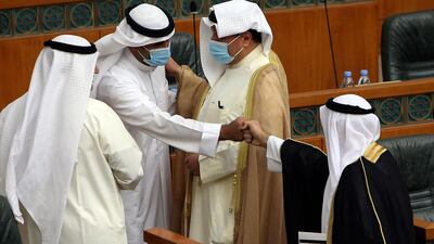 Kuwaiti MPs wearing protective masks greet each other at the start of a parliamentary session at the National Assembly in Kuwait City. AFP