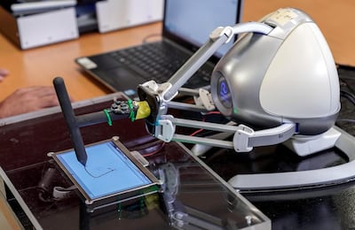 An earlier version of the device was a robotic arm that physically guides the hand. Victor Besa / The National