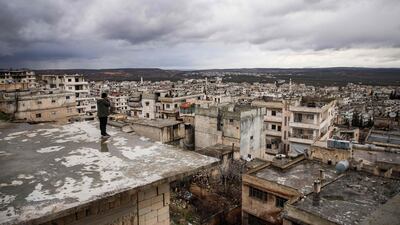 TOPSHOT - A man takes a picture with a camera while standing atop the roof of a building in a deserted area of the town of Ariha, about 13 kilometres south of Idlib in the northwestern Syrian Idlib province on February 7, 2020, after most residents fled due to bombardment by approaching government forces. / AFP / AAREF WATAD