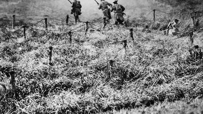 US troops advance on a path through a barbed wire entanglement near Beauqueanes, Somme, France.