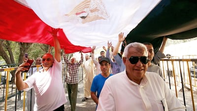 Egyptian nationals living in Kuwait pass under their country's national flag as they prepare to cast their votes in a referendum on constitutional amendments at the Egyptian embassy in Kuwait City. AFP