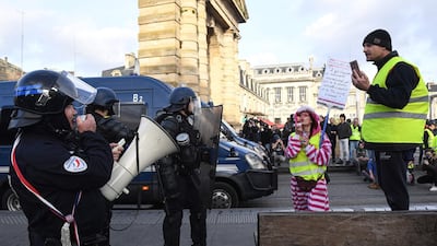 A protester blows bubbles next to gendarmes and police during a Yellow Vest anti-government demonstration in Bordeaux. AFP