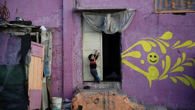 A Palestinian boy hangs on a door of his home that was painted by artists.