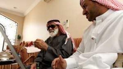 Mohammed Salem al Dhaheri, right, from Al Ain Municipality, helps Ali Saeed at his home.