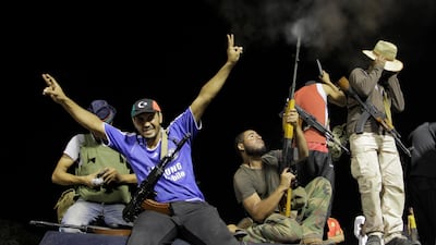 Rebel fighters gesture and shoot in the air as they celebrate overrunning Moammar Gadhafi's compound Bab al-Aziziya in Tripoli, Libya, early Wednesday, Aug. 24, 2011. Hundreds of Libyan rebels stormed Gadhafi's compound Tuesday, charging wildly through th???