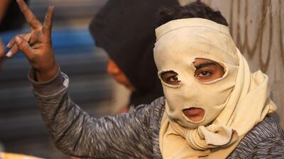 An Iraqi boy wearing a makeshift mask flashes the victory gesture during clashes between anti-government protesters and security forces in the Iraqi capital Baghdad's Rasheed street near al-Ahrar bridge. AFP