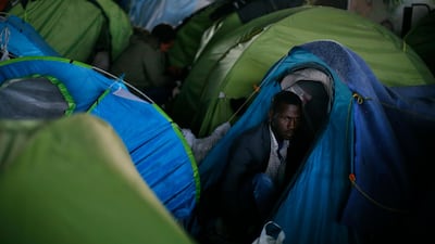 A migrant stands in his tent during the evacuation of a makeshift camp, in Paris, France. Authorities moved in early Wednesday to the so-called Millennaire tent camp on the city's edge alongside a canal used by joggers and cyclists. It is the largest of several around Paris. Thibault Camus / AP Photo