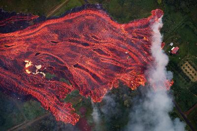 A massive fast moving lava flow consumes everything in its path, as the flames from the remnants of one home burns on the left, while it approaches another on the right. Pahoa, Hawaii, 19 May 2018. The ongoing eruption of Kilauea is the largest in decades, destroying more than 40 homes to date, and displacing thousands. Bruce Omori / EPA