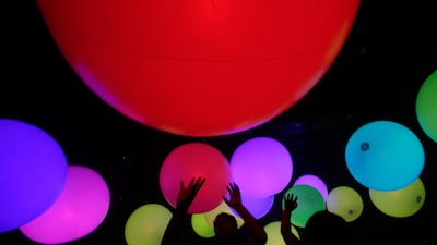 Visitors at the Jungle and Future Park in Tokyo reach out to touch colourful balloons known as "sound spheres" in an art and interactive music installation by teamLab. Shizuo Kambayashi / AP Photo