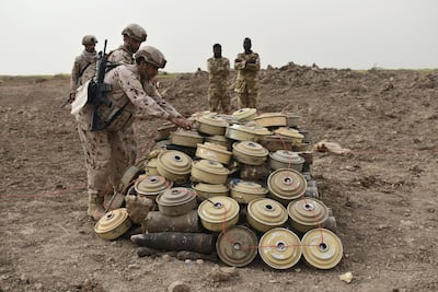 UAE minesweepers lay ignition cord across a cache of Houthi landmines, as two Sudanese colleagues look on. Gareth Browne/The National