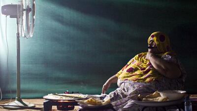 Zahra Al Balooshi, matriarch of the family, makes khobz regag by a camping stove. Khobz regag, an Arabian Gulf tradition, is a thin, delicate home-made bread.