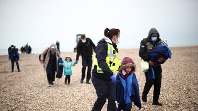 Migrants are escorted by Border Force staff in Dungeness, after being brought ashore by an RNLI lifeboat. Reuters