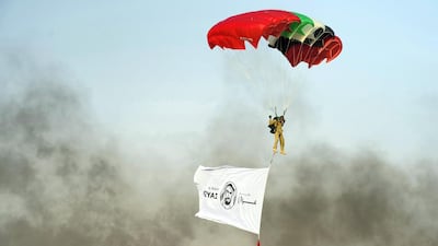 A soldier parachutes down carrying a Year of Zayed banner. Wam