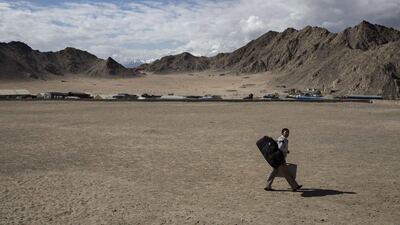 An election worker carries a voting machine and his overnight bag as he leaves a central collection point to head for a polling station.
