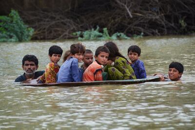 A man uses a satellite dish to move children across a flooded area after heavy monsoon rains in Pakistan last August. The country has had to receive more than $8 billion in support from donors. AFP