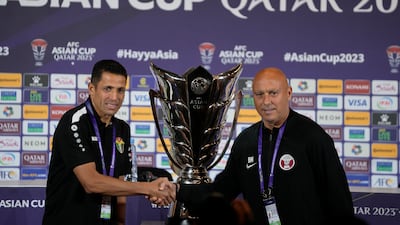 Jordan's head coach Lhoussanine Ammouta, left, and Qatar's head coach Bartolome Marquez shake hands in front of the Asian Cup trophy ahead of a press conference in Doha, Qatar, Friday, Feb. 9, 2024. Jordan will play Qatar on Saturday for the soccer final of the Asian Cup. (AP Photo / Thanassis Stavrakis)
