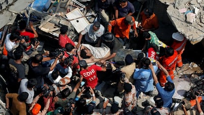 Rescue workers recover an injured man from the rubble of the three-story residential building, which collapsed before dawn in a poor neighbourhood of the port city. Akhtar Soomro / Reuters