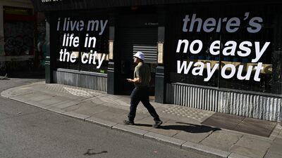 A person wearing a bucket hat, made famous by British band Oasis, walks past a shop with the lyrics from one of the group's songs, in Manchester, northern England, ahead of the second leg of their highly anticipated reunion tour. AFP