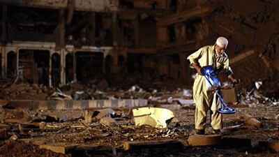 A man sorts through debris in the car park of the Pearl Continental Hotel in Peshawar, where suicide bombers detonated a lorry full of explosives.