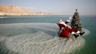 Issa Kassissieh, wearing a Santa Claus costume, sits next to a Christmas tree on a salt formation in the Dead Sea near Ein Bokeq. Reuters