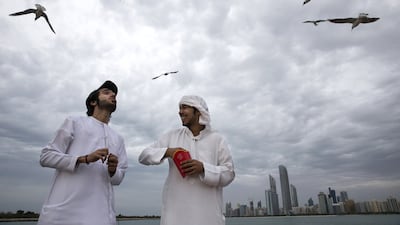 (L) Hmaid al Qubaisi and (R) Jasem al Dahrei share their french fries with seagulls. Silvia Razgova / The National
