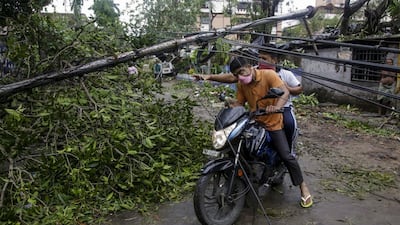 People make their way through damaged cables and a tree branch fallen in the middle of a road after Cyclone Amphan hit the region in Kolkata, India. A powerful cyclone ripped through densely populated coastal India and Bangladesh, blowing off roofs and whipping up waves that swallowed embankments and bridges and left entire villages without access to fresh water, electricity and communications. AP Photo