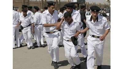 Egyptian police officers help an injured colleague outside the Police Military Academy complex in Cairo during the trial of Egypt's ousted President Hosni Mubarak. In the wake of the anti-Mubarak revolt, many in Egypt's police force are trying to keep the pervasive power they held under his nearly 30-year regime. Nasser Nasser / AP Photo