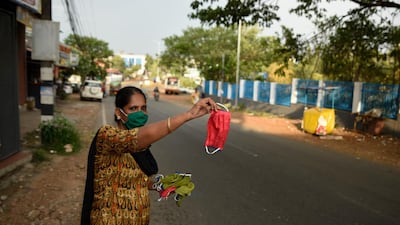 A woman waves a face mask to attract prospective buyers among commuters as she sells them outside a shop in Kochi, Kerala. AP Photo