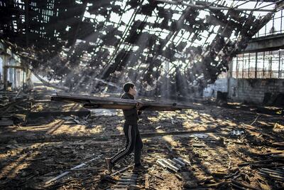 An Afghan migrant collects wood to make a bonfire in an abandoned factory in the Bihac industrial area. JM Lopez / The National