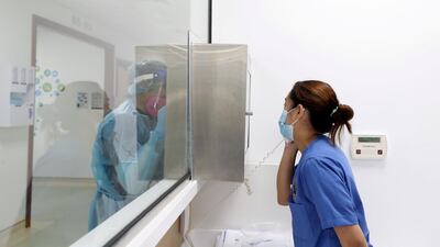 Staff speak to each other during a shift through a glass window dividing the ICU ward from the nurses station.