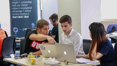 Saber Ghaith, left, Andrey Simeonov, centre, and Danni Luq discuss their team project at the Dubai Startup Weekend at Astrolabs Dubai. Victor Besa for The National