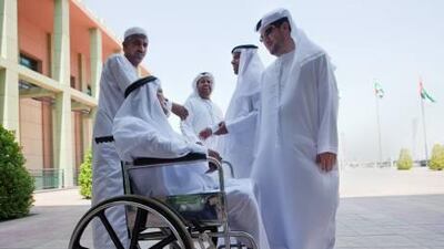 Yousef Mohammed, 55, in wheelchair, talks with friends after voting at the Ministry of Culture in Umm Al Qaiwain.