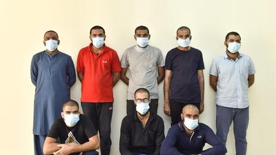 Eight of the men, along with laptops and phones seized by police. Courtesy Sharjah Police