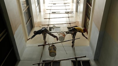 Decorators paint the wall of a building while hanging from a bamboo ladder in Dhaka, Bangladesh. Abir Abdullah / EPA