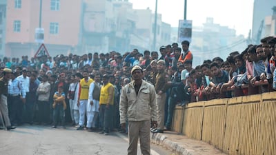 A Police personnel stands guard along a road as onlookers gather following a factory fire in Anaj Mandi area of New Delhi. At least 43 people have died in a factory fire in India's capital New Delhi, with the toll still expected to rise. AFP