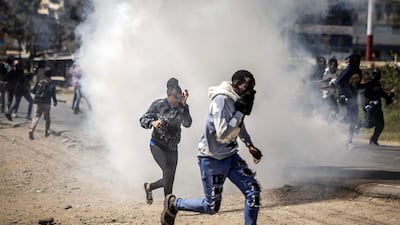 Protesters take cover amid tear gas fired by Kenyan police officers. AFP