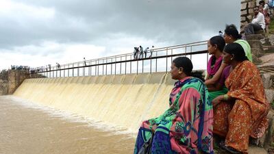 Indian villagers sit near the overflowing Laknapur Project irrigation channel following heavy rain in the Parigi Mandal area of Ranga Reddy District in Hyderabad, India. Noah Seelam / AFP