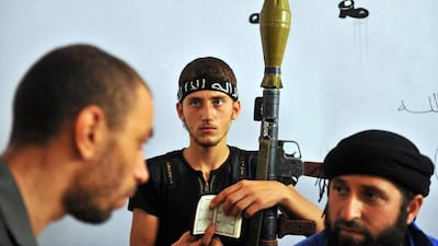 A young fighter from the Syrian opposition holds a Quran in one hand and a rocket-propelled grenade in the other, as other rebels rest in the school. Bulent Kilic / AFP Photo
