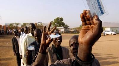 South Sudanese men hold voting registration cards as they wait in the line to vote at a polling station during the referendum in Juba, south Sudan.