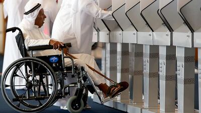 An official helps an elderly voter at the Umm Al Quwain polling centre. Satish Kumar / The National