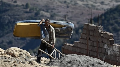A man carries some of his belongings after his home was destroyed in the earthquake in Moulay Brahim. AFP