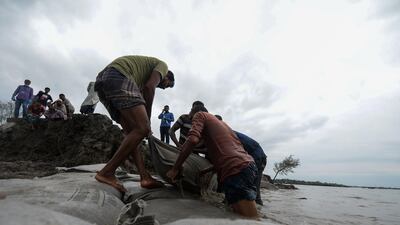 Volunteers and residents place sack filled with soil to repair a damaged dam following the landfall of cyclone Amphan in Burigoalini. At least 84 people died as the fiercest cyclone to hit parts of Bangladesh and eastern India this century sent trees flying and flattened houses, with millions crammed into shelters despite the risk of coronavirus. AFP