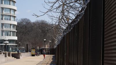 A woman jogs next to a barbed wire security fence near the US Capitol building. Willy Lowry / The National