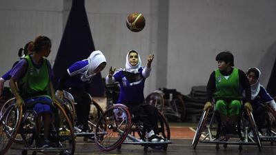 The Afghanistan's women's wheelchair basketball team (in blue) playing against Thailand during a training session. Lillian Suanrumpha / AFP Photo