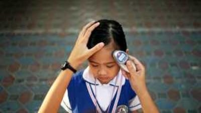 A nurse checks the temperature of each student before they enter the classroom at the Philippine National School.