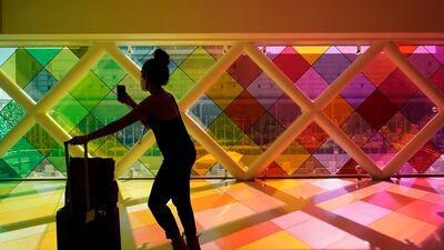 A traveller takes photos of windows titled "Harmonic Convergence," by artist Christopher Janney, at Miami International Airport in Miami. The Greater Miami Convention and Visitors Bureau is anticipating hotel occupancy levels to surge above pre-pandemic levels. AP Photo