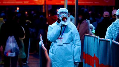 A staff member in a protective suit speaks through a loudspeaker ahead of the 2020 Shanghai marathon. AFP