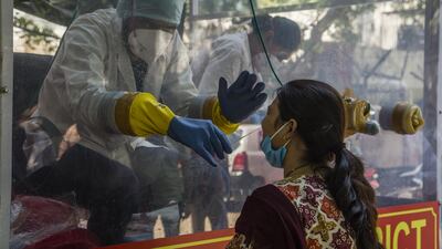 An Indian health official inside a Covid-19 mobile testing van in New Delhi uses a nasal swab to collect a sample from a woman. Getty Images