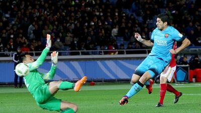 Luis Suarez, right, kicks the ball past Guangzhou Evergrande’s goalkeeper Li Shuai to score. Eugene Hoshiko / AP Photo